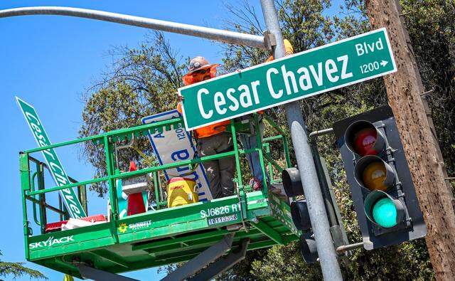 A work crew installs a new Cesar Chavez Boulevard sign in place of a Ventura Avenue sign at C Street in Fresno in 2024. City officials have called to change the street’s name following a bombshell report published by The New York Times alleging Chavez abused young women and girls for years.